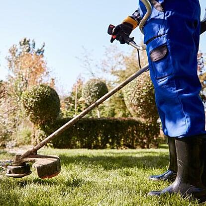 Lawn care technician holding trimmer and using field service software for small business scheduling