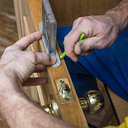Locksmith installing door lock using cloud-based field service software to manage mobile jobs and payments